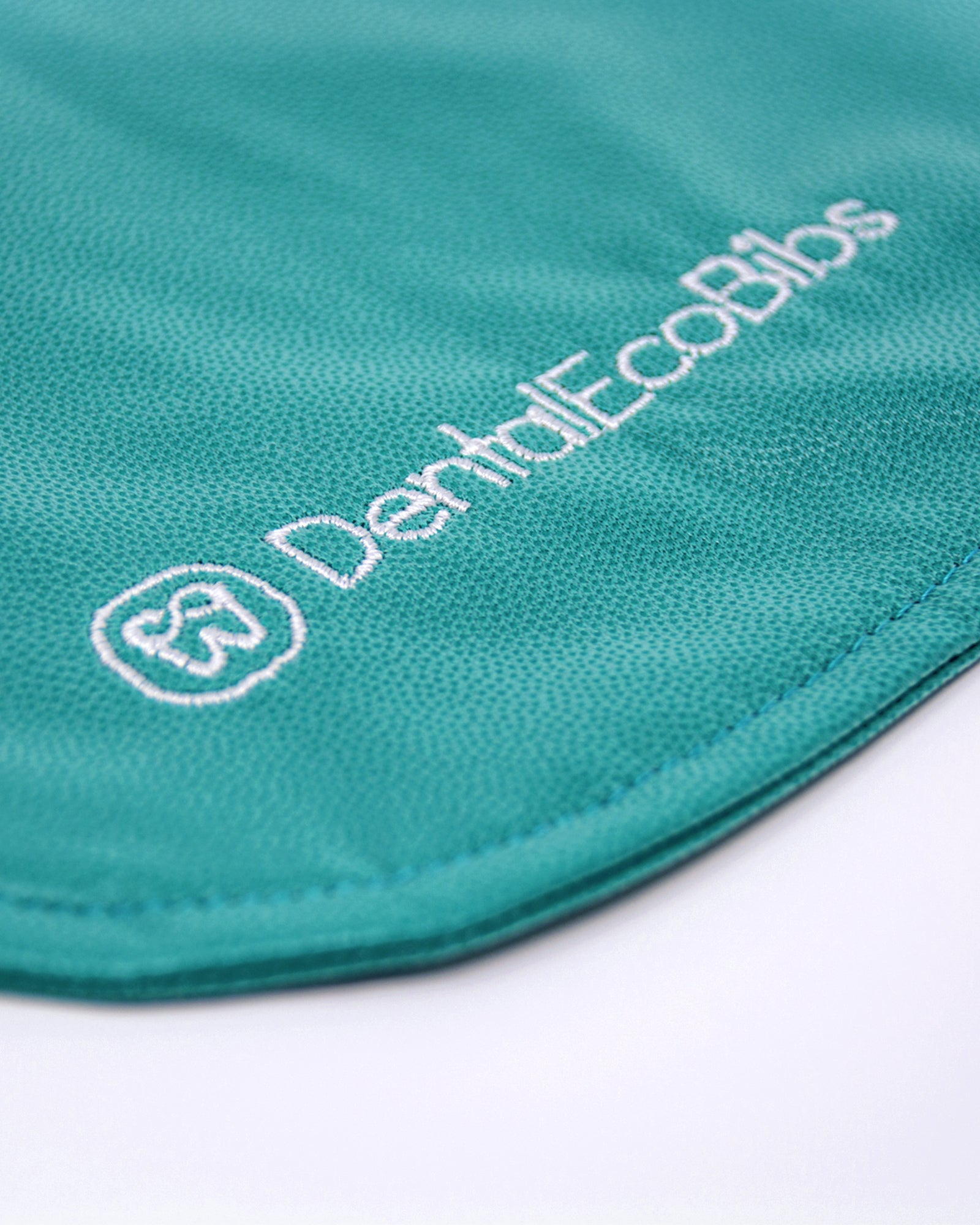 Close-up of a teal reusable dental bib with the DentalEcoBibs logo.