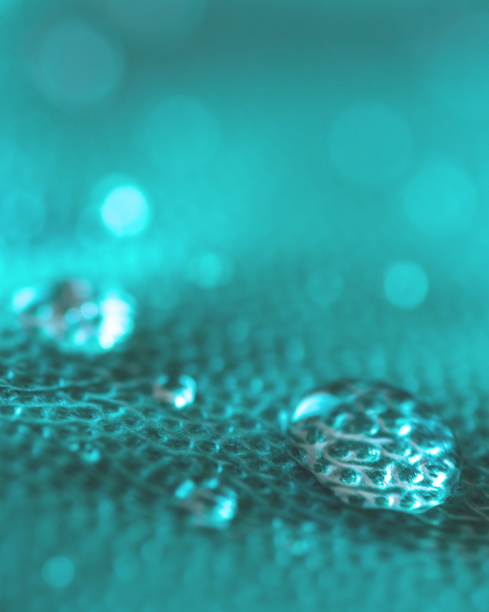 Close-up of water droplets on a teal waterproof background.